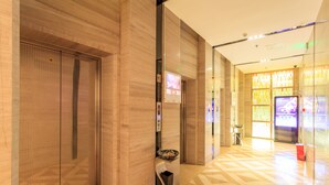 An interior corridor with a patterned floor, a glass wall with a digital display, and a trash bin. - Chengdu Tu Le Apartment (Chengdu)
