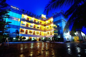 Um hotel com vários andares, uma placa de destaque, várias varandas e uma área de entrada bem iluminada.