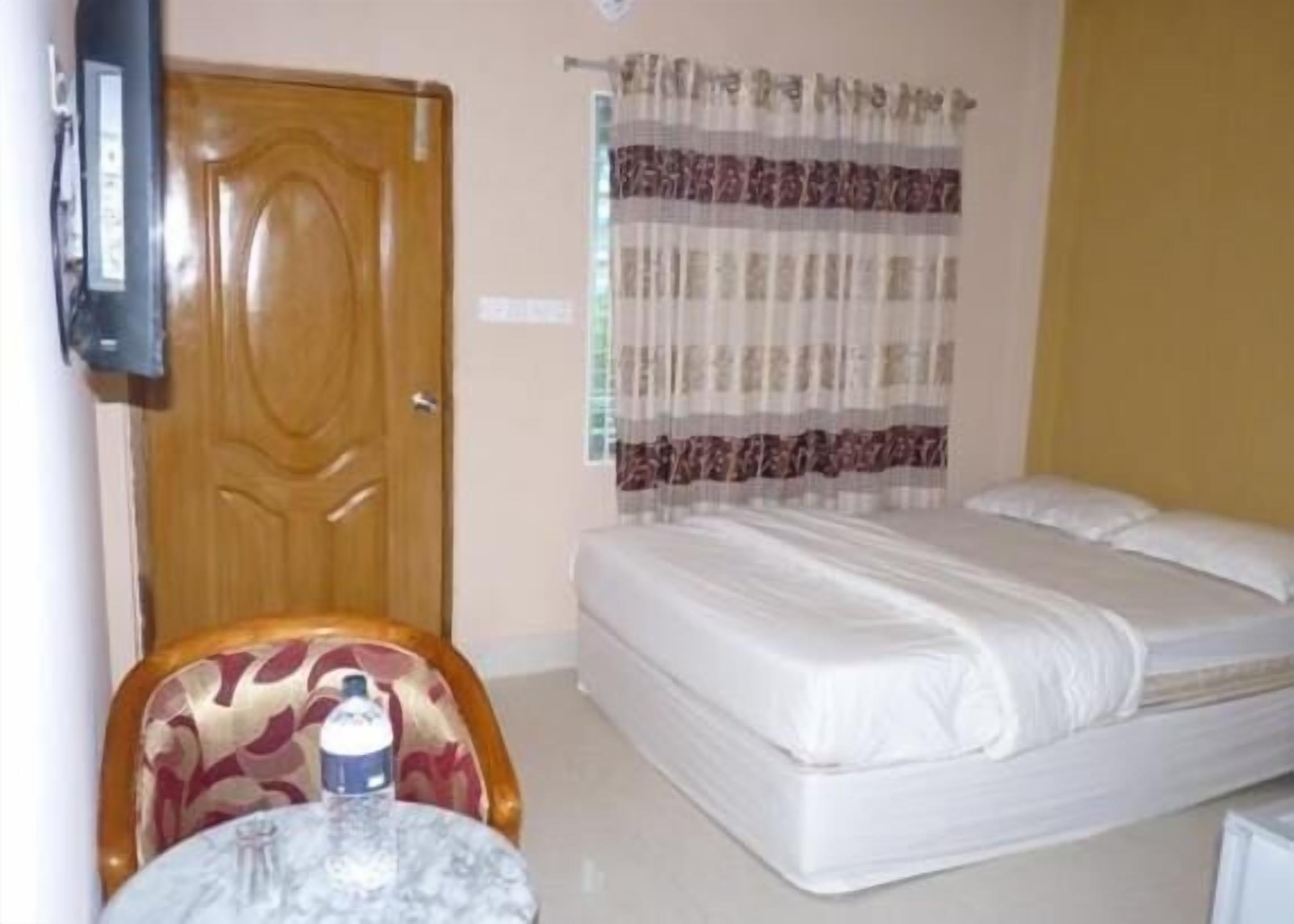 A hotel room with a bed, a chair, a small table, and a television.