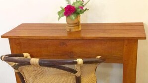 Une table en bois, avec une chaise en osier placée devant.