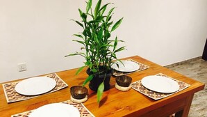 Une table à manger en bois, avec quatre assiettes blanches et une plante en pot placée au centre.