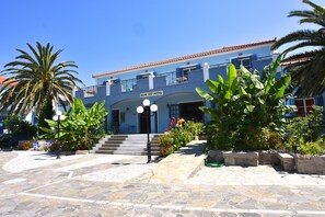 A hotel with a blue facade, a tiled entrance, and a sign reading "Blue Sky Hotel".