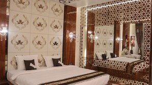 A hotel room with a large bed, a mirror, and patterned wallpaper.