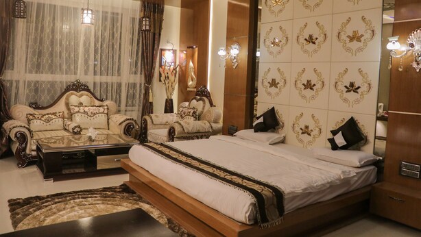 A spacious bedroom with a large bed, two sofas, a coffee table, and a mirror.