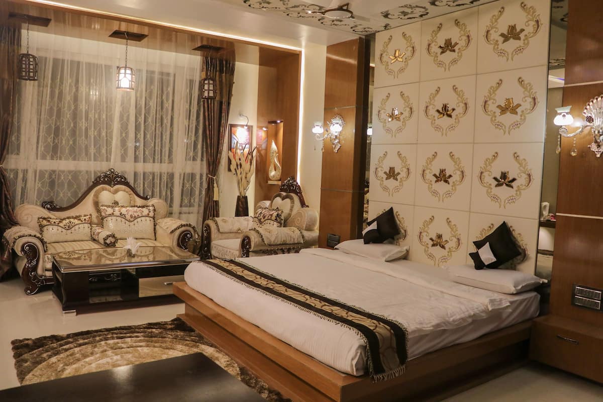 A spacious bedroom with a large bed, two sofas, a coffee table, and a mirror.