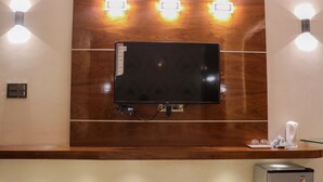 Un espace d’accueil doté d’un téléviseur à écran plat fixé à un mur en bois, de part et d’autre duquel se trouvent des lampes murales.