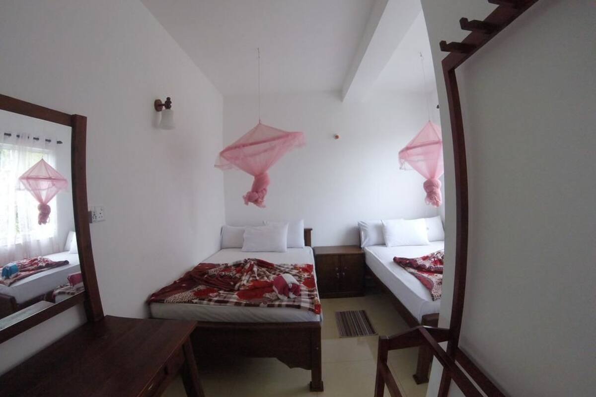 Une chambre à coucher avec un lit, des tables de chevet, un miroir et une fenêtre avec des rideaux.