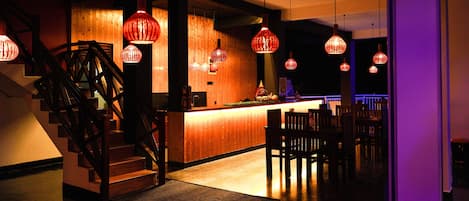 A modern interior with a wooden staircase, a bar area, and hanging red lanterns.