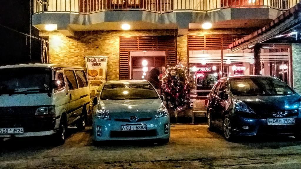 A building with a sign for 'Fresh Fruit Juice' and a Christmas tree. There are three cars parked in front.