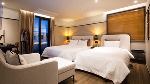 Une chambre d’hôtel avec deux lits, un bureau, une chaise et une vue sur l’extérieur.