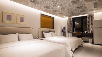 A hotel room with two beds, a desk, a mirror, and a window with curtains.