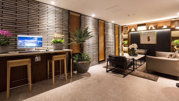 Un salon moderne avec un mur décoré d’un motif en briques, un téléviseur, une table basse, un canapé et un coin repas avec un bar.