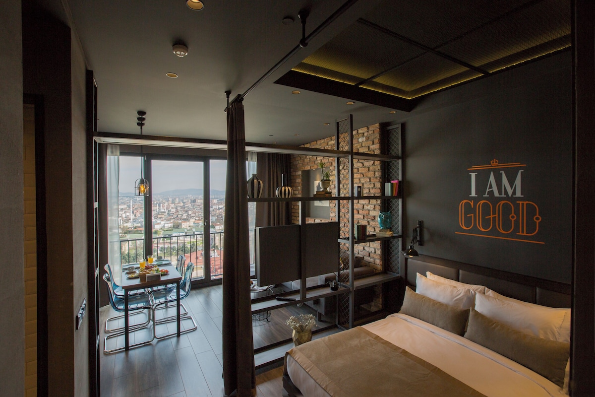 A modern hotel room with a large bed, a TV, and a balcony with a city view.