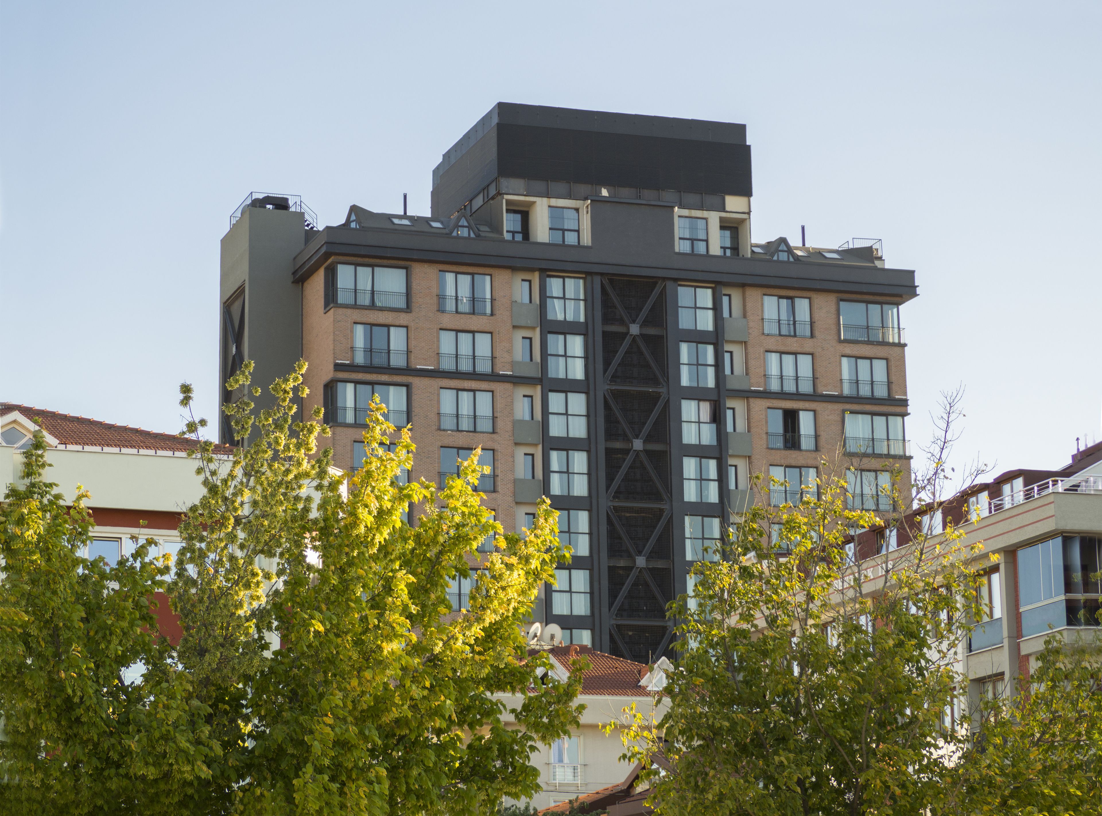 Un immeuble à plusieurs étages doté d’une architecture moderne, caractérisé par une tour centrale imposante et de nombreux balcons.