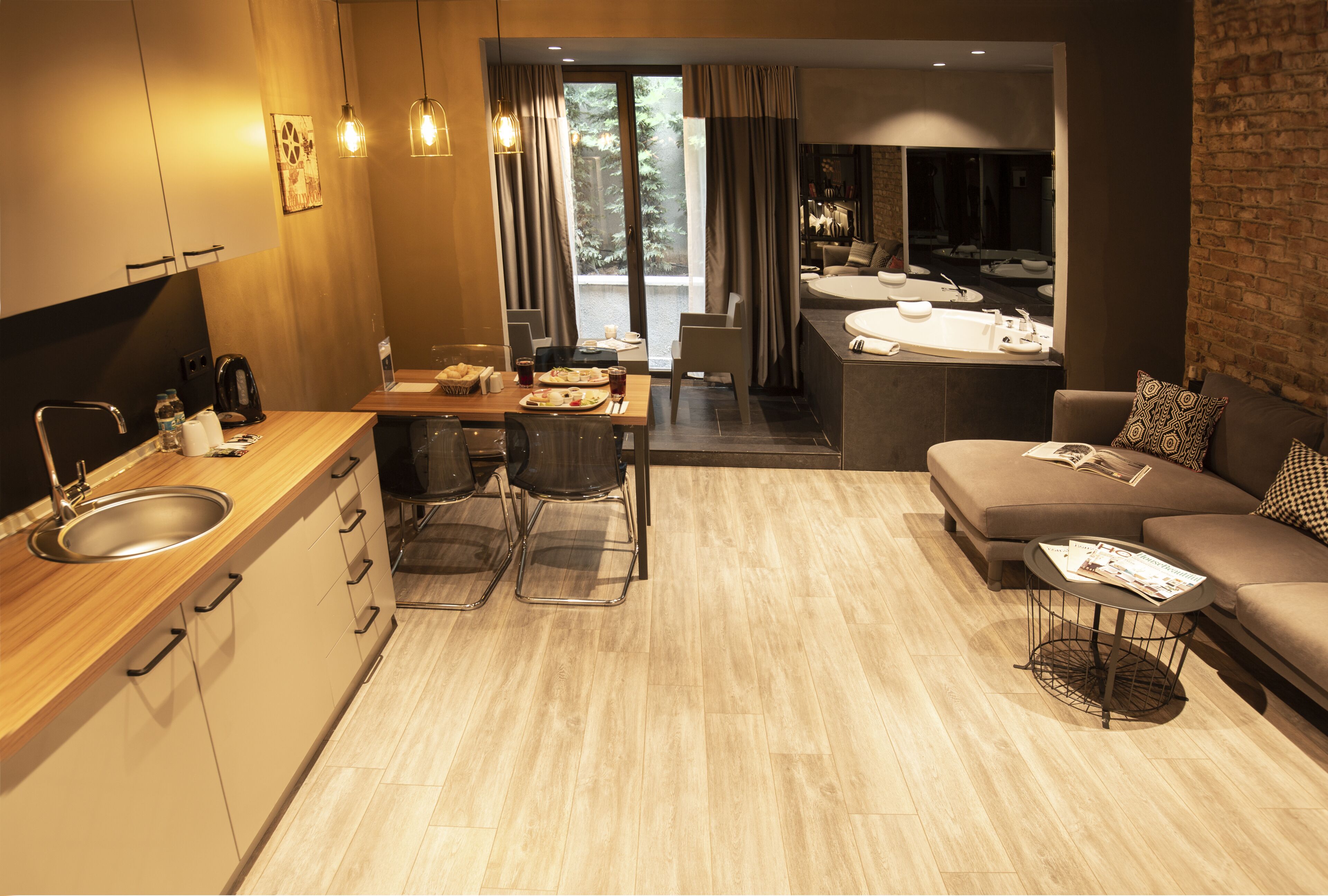 A modern hotel room with a kitchen, dining area, and living space.
