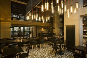 A modern interior with a checkered floor, multiple dining tables and chairs, hanging light fixtures, and a visible reception desk. - Cityloft 161 (Istanbul)