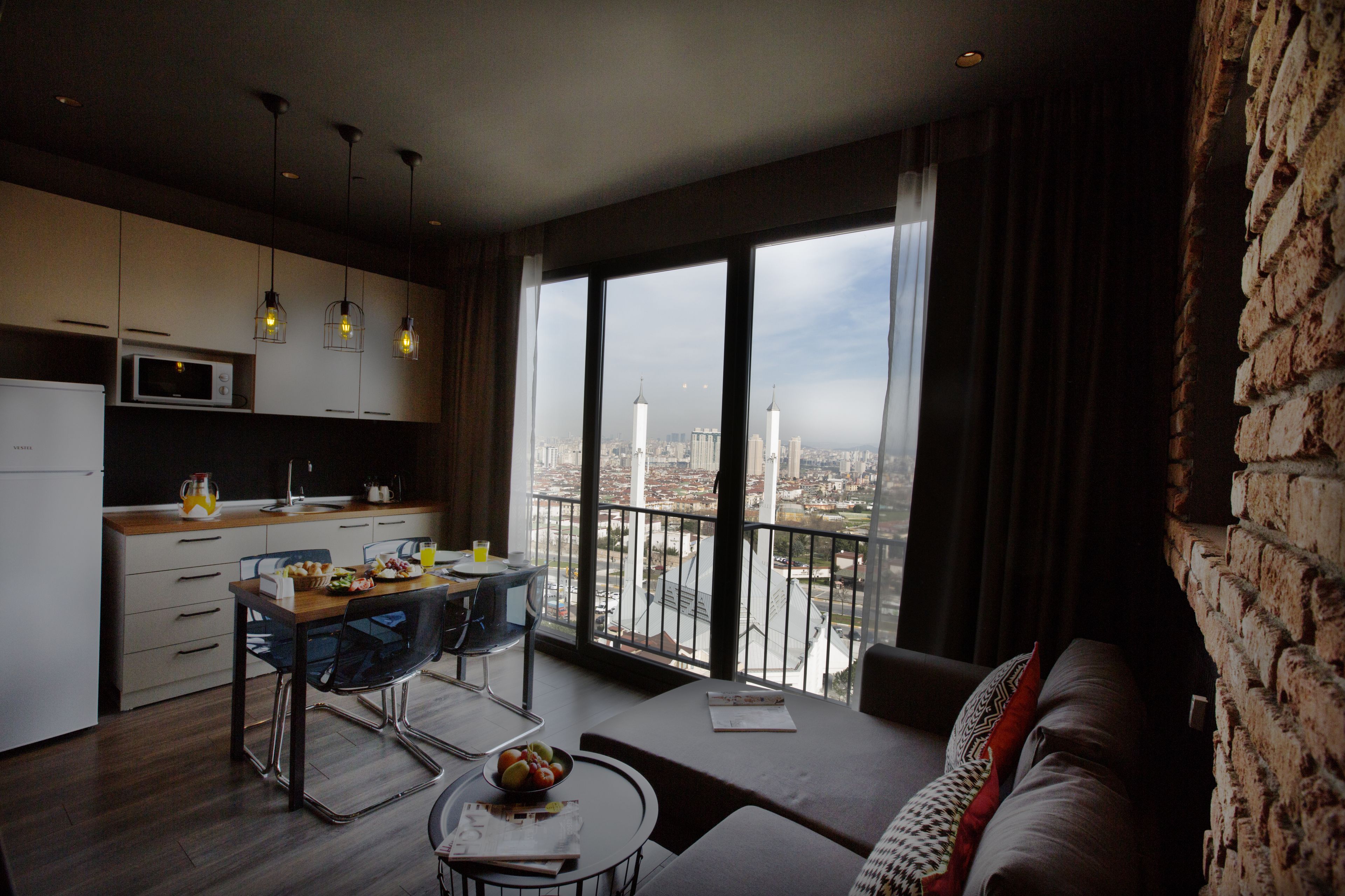 Una cocina moderna con zona de comedor, un sofá y un amplio ventanal con vista a la ciudad.