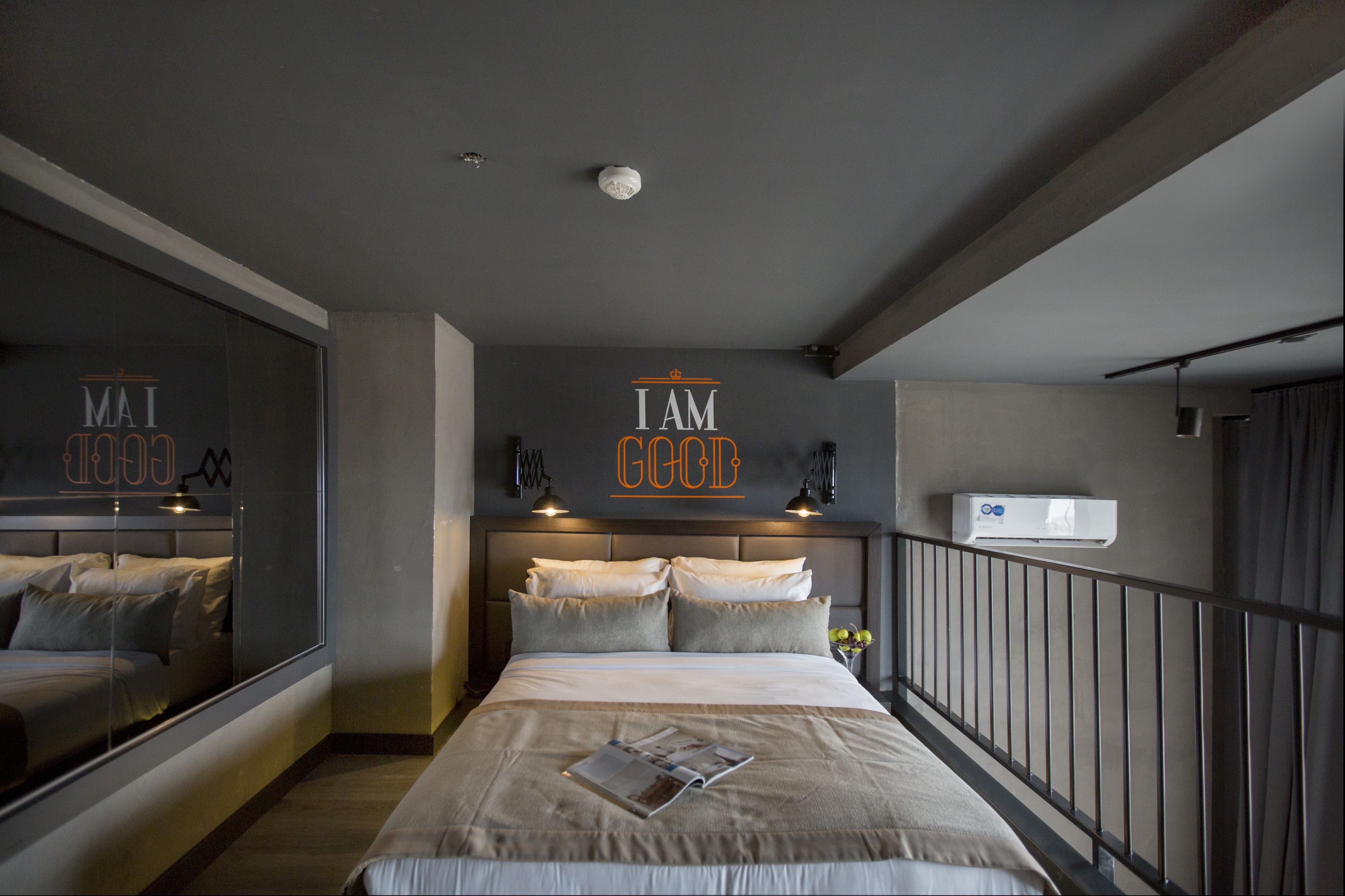 Een moderne slaapkamer met een groot bed, een spiegel en een motiverende quote op de muur.
