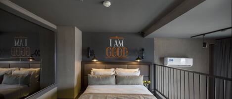 A modern bedroom with a large bed, a mirror, and a motivational quote on the wall.