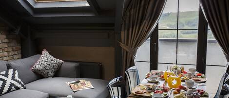 Una habitación moderna con sofá, mesa de comedor y vista a un lago.