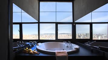 Une salle de bain avec une grande baignoire, une fenêtre donnant sur la ville et une serviette accrochée sur le côté.