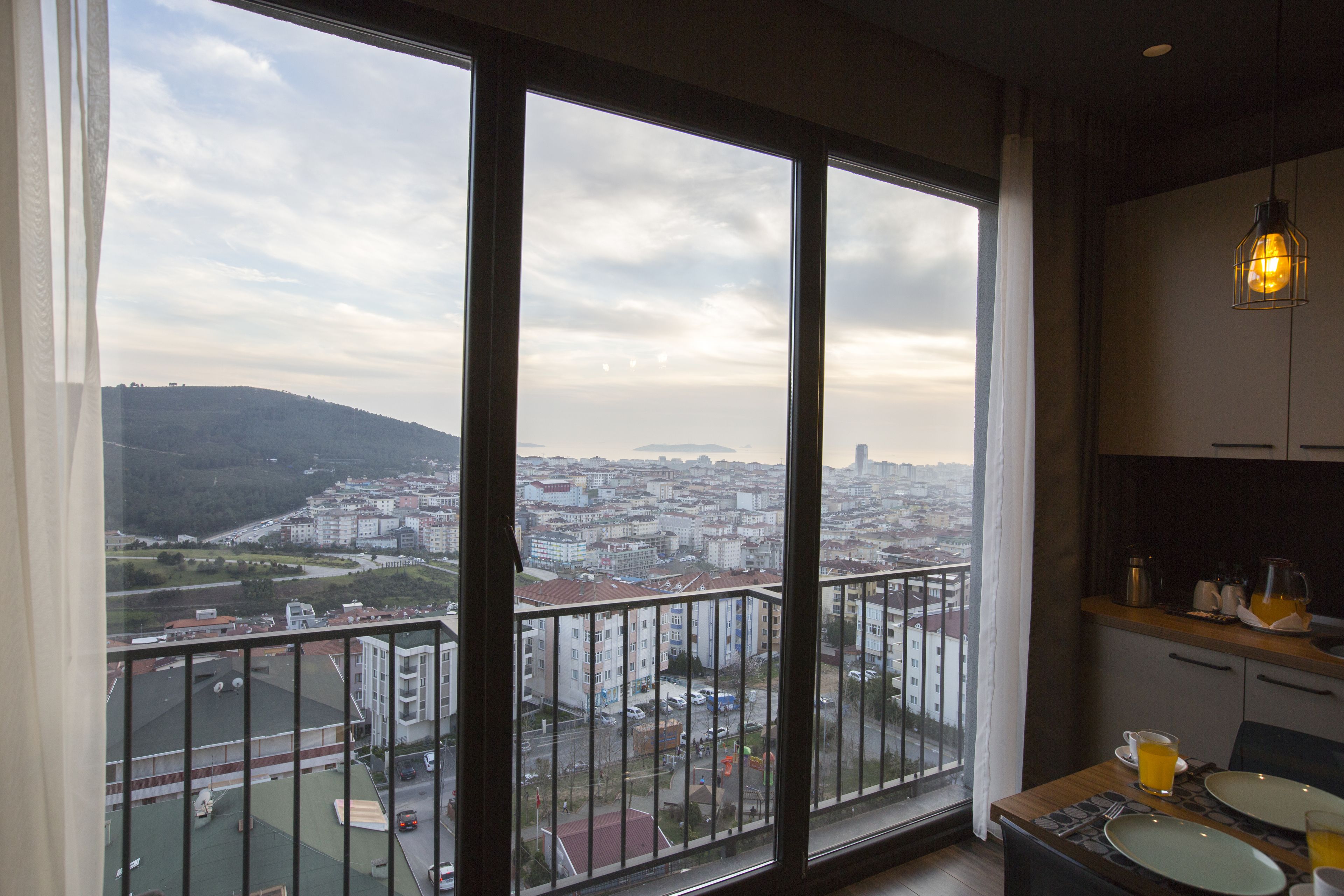 Un balcon avec vue sur la ville, un coin repas avec une table dressée et un luminaire suspendu.