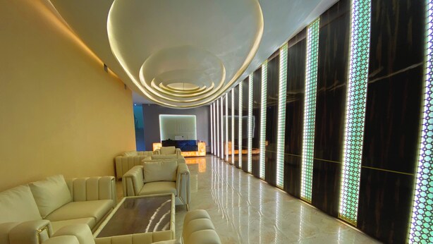 A modern lobby with a seating area, a reception desk, and large windows with patterned glass.