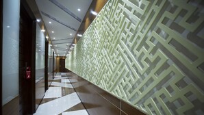 A hallway with a geometric patterned wall, a checkered floor, and recessed lighting.