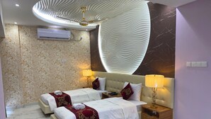 A hotel room with two beds, a ceiling fan, an air conditioning unit, marble flooring, and a decorative wall.