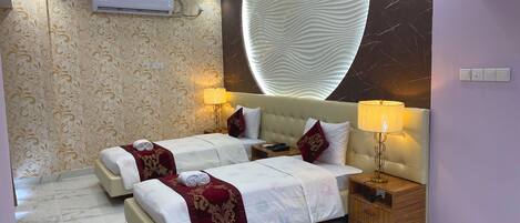 A hotel room with two beds, a ceiling fan, an air conditioning unit, marble flooring, and a decorative wall.
