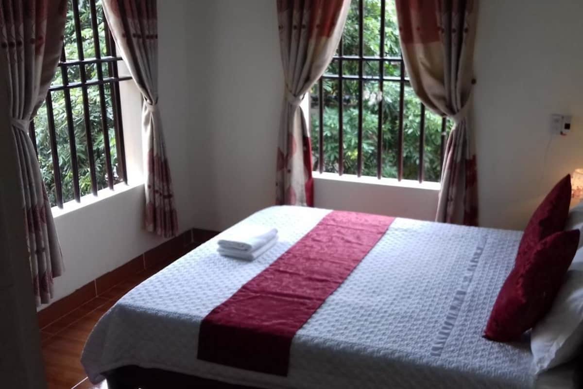 A neatly made bed with a white and red bedspread, a red pillow, and a white towel on the side.