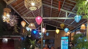 A group of people dining at an indoor restaurant with a high ceiling and hanging lanterns. - Tam Coc Family Hotel Ninh Binh (Nam Hoa Lu)