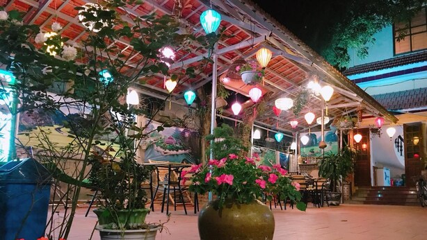 An outdoor seating area with tables and chairs, surrounded by potted plants and a large vase. - Tam Coc Family Hotel Ninh Binh (Nam Hoa Lu)