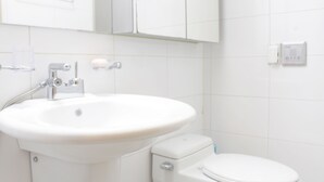 Ein Badezimmer mit weißem Waschbecken, Toilette und einem Spiegel über dem Waschbecken.
