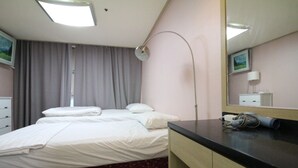 Ein Hotelzimmer mit Bett, Nachttisch, Spiegel und einem Fenster mit Vorhängen.