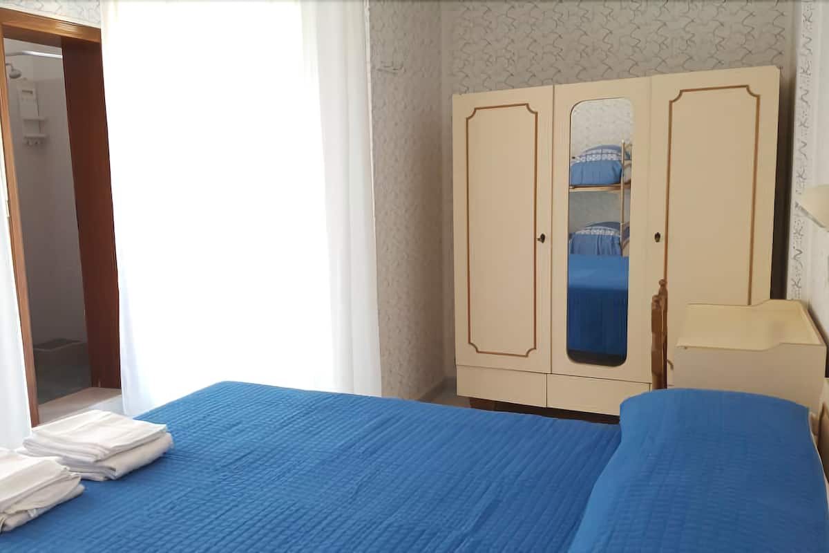 A bedroom with a bed, a wardrobe, and a mirror.