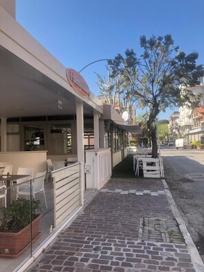 A restaurant with outdoor seating, a covered patio, and a street view. - Hotel Pensione Elena (Misano Adriatico)