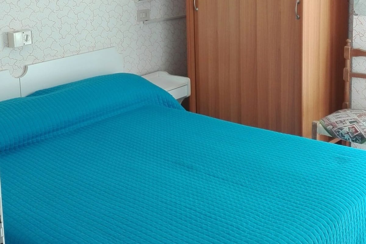 A bedroom with a bed, a wardrobe, and an air conditioning unit.