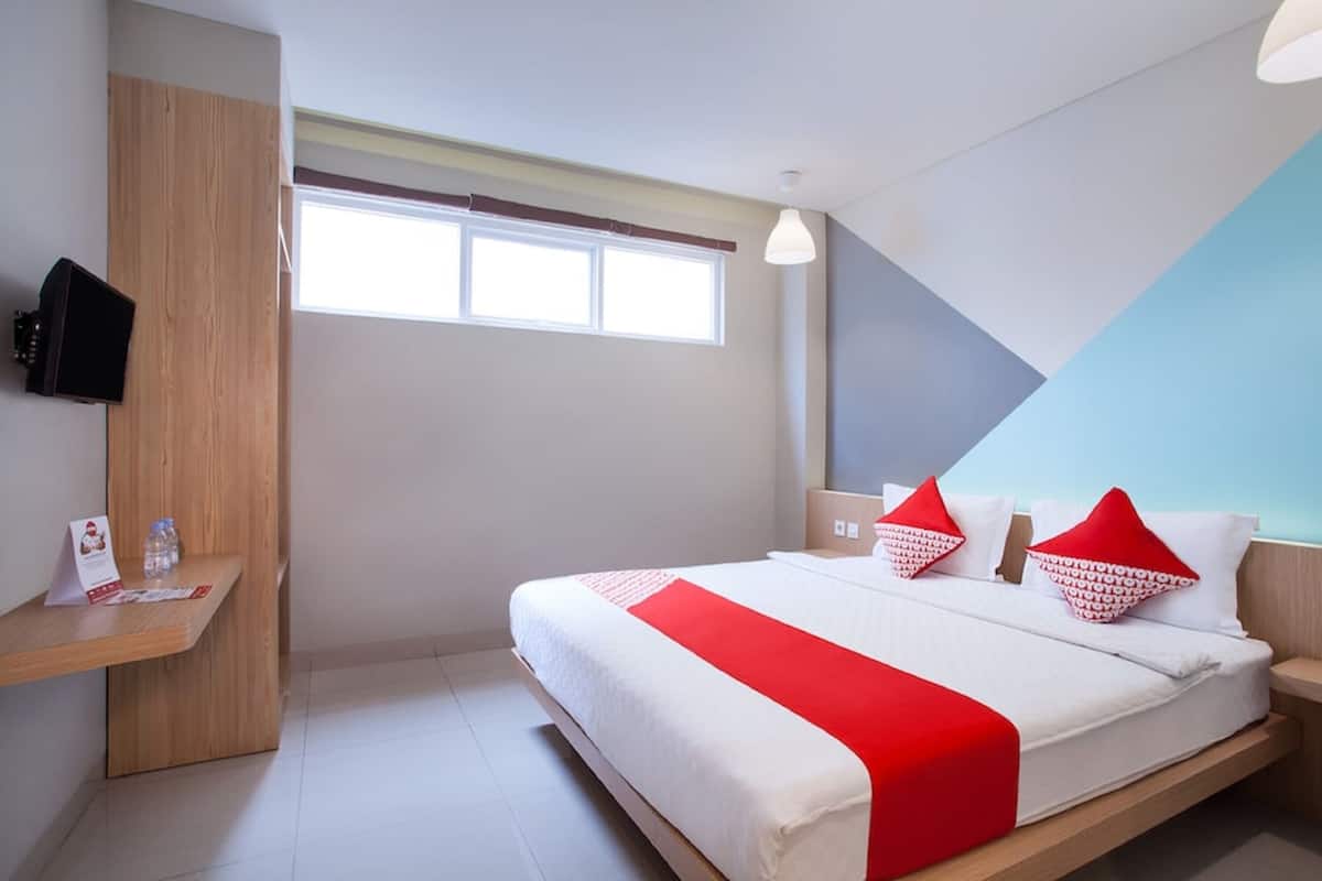 Une chambre d’hôtel moderne, dotée d’un grand lit, d’un bureau et d’une télévision.