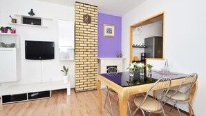 A modern dining area with a wooden table, metal chairs, and a purple accent wall. - Apartments Markic (Seget)