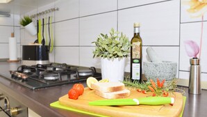 A kitchen counter with a cutting board, a bottle of olive oil, a mortar and pestle, and some fresh produce. - Apartments Markic (Seget)