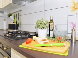 Prepare fresh meals in this well-equipped kitchen with a stainless steel stove, utensils, and a cutting board.