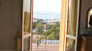 A room with a view of a marina and boats, a wooden floor, and a mirror on the wall. - Villa delle Rocce (Olbia)