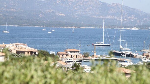 A marina with boats, a mountain in the background, and buildings along the shore. - Villa delle Rocce (Olbia)