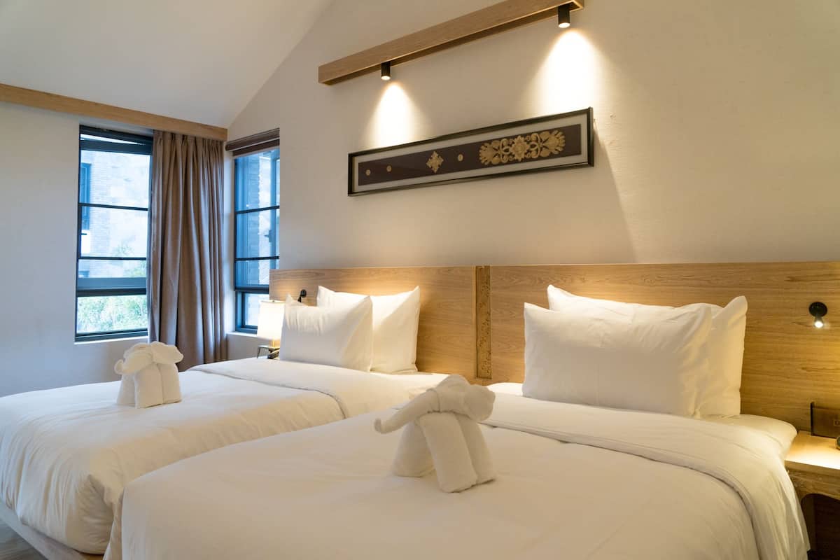 Habitación de hotel con dos camas, un ventanal grande y un adorno en la pared.