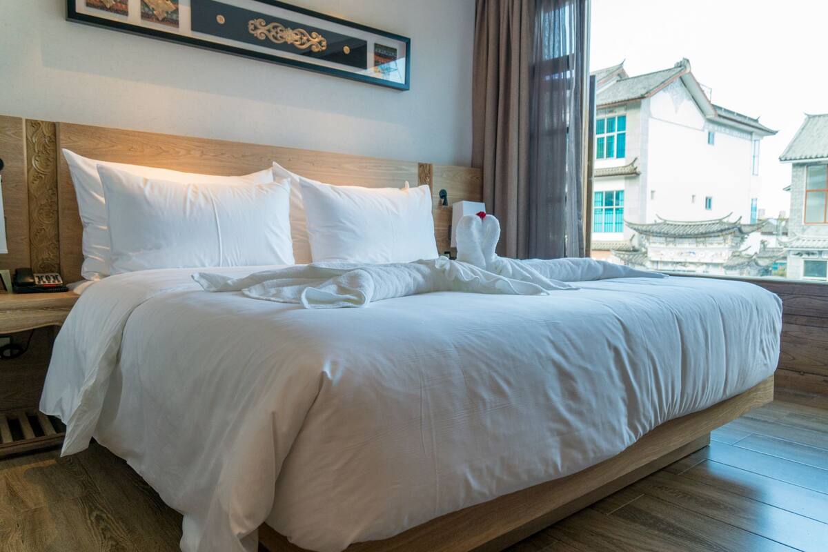 Habitación de hotel con una cama grande, cabecero de madera y vistas a la arquitectura tradicional.