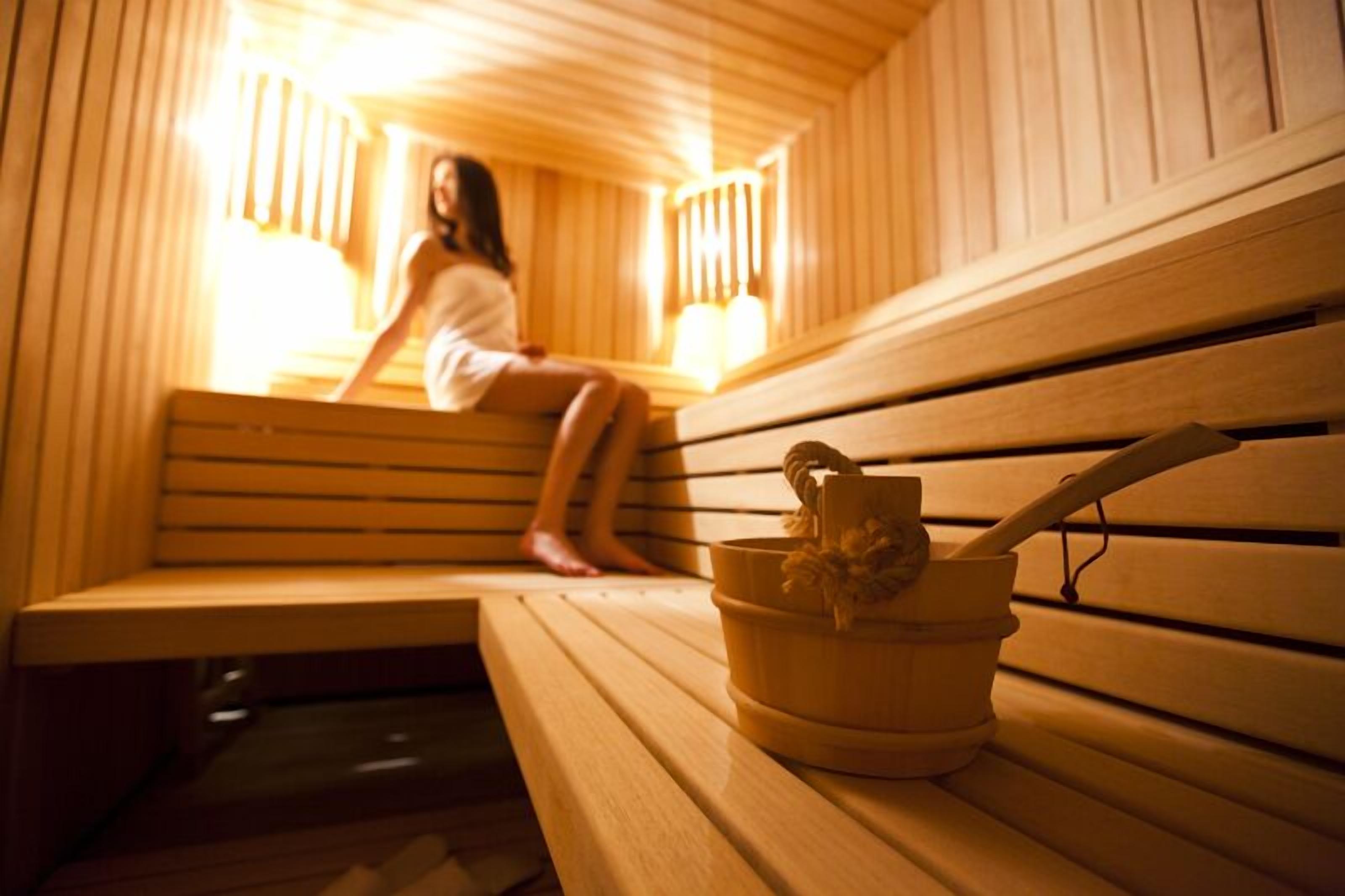 Una sauna de madera con bancos y un balde con un cepillo.