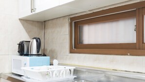 A kitchen with a stainless steel sink, a microwave, a kettle, and a window with a wooden frame. - Seoul Galleria (Seoul)