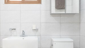 A bathroom with a white sink, a toilet, a window with a wooden frame, and a mirror cabinet. - Seoul Galleria (Seoul)