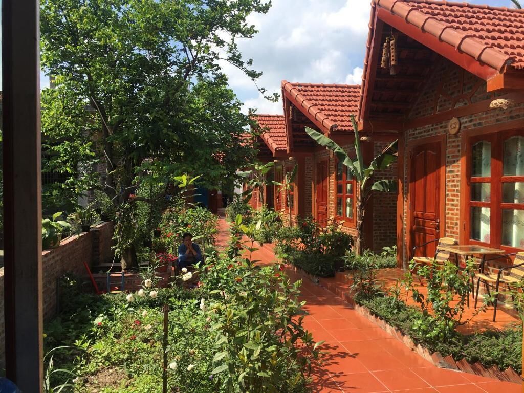 Um pátio com edifícios de tijolo, um caminho e vegetação exuberante.